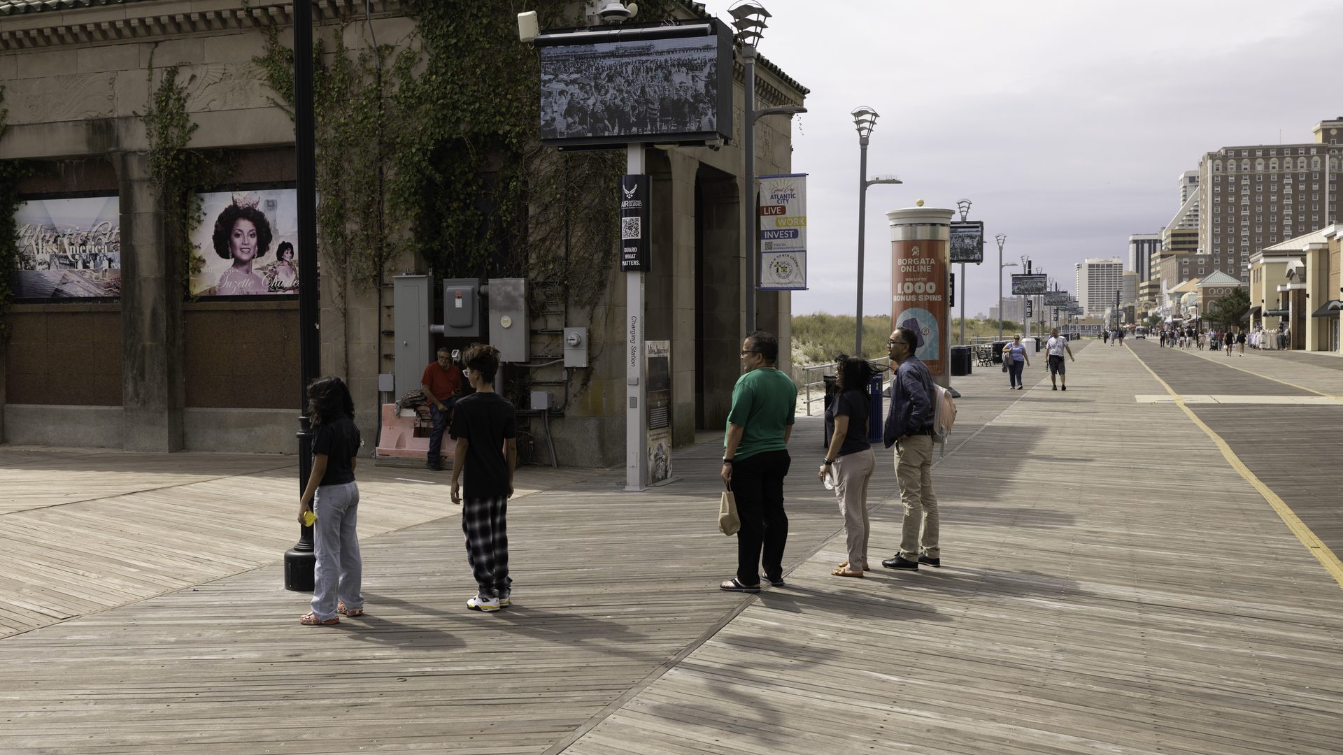 APM poster displays along a Boardwalk storefront frontage with visitors walking past